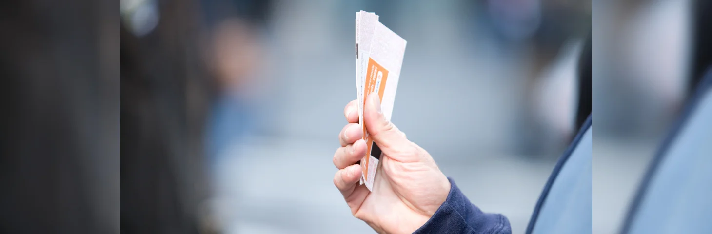 A hand holding tickets to an event.