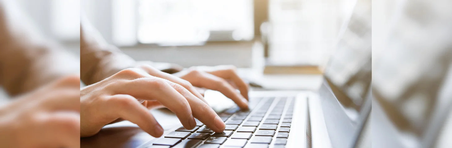 Two hands typing on a laptop.