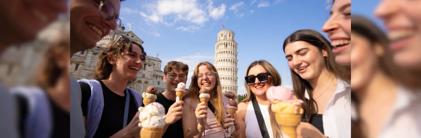 Image of a group of young travellers outside the Tower of Pisa eating gelato