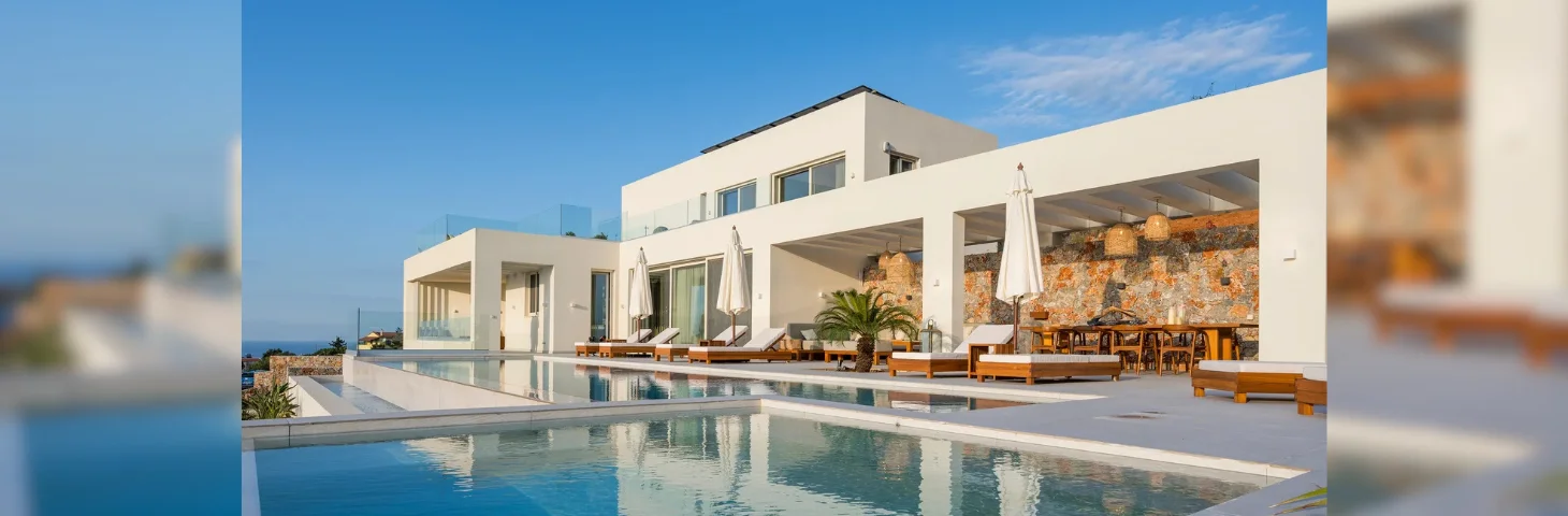 The outdoor pool area at Villa Rhea in Peyia, Cyprus, with a blue sky in the background.