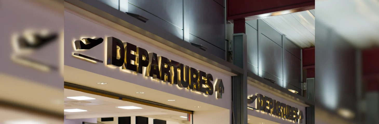 A sign guiding guests towards the Departures area at Luton Airport. 